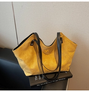 Detail view of yellow quilted suede tote bag with golden twist lock and black strap