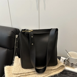Minimalist black leather bucket bag with wide shoulder strap and gold A-buckle detail