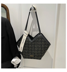 Close-up of black and gold tweed bucket bag featuring a V-shaped top and contrast straps
