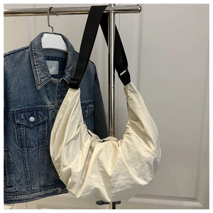 Détail du sac bandoulière croissant crème avec texture plissée sur cintre en métal