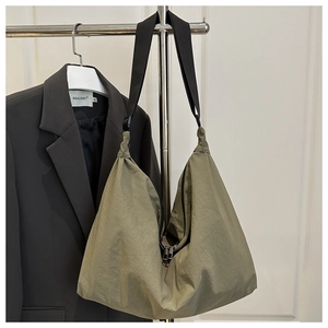 Detail of olive green nylon hobo bag featuring dual metal zippers and adjustable strap