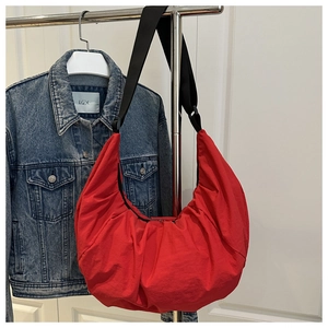 Détail du sac rouge plissé avec large bandoulière noire dans un décor de style de vie