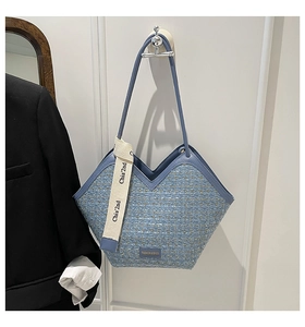 Detail of blue tweed tote bag featuring V-shaped cut and beige woven decorative strap