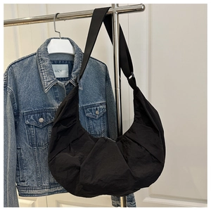 Gros plan du sac croissant en nylon plissé noir avec large bandoulière et cintre métal