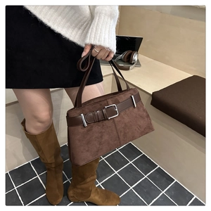 Close-up of brown suede tote bag featuring leather belt strap and silver metal buckle detail