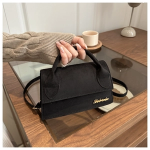 Detail of black mini crossbody bag with gold logo on suede texture and slim shoulder strap