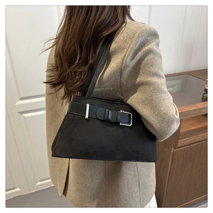 Side view of large black matte shoulder bag worn by model in a stylish office outfit