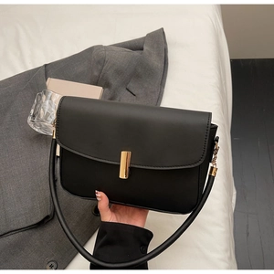 Detail of black leather handbag featuring a golden lock clasp and multiple compartments
