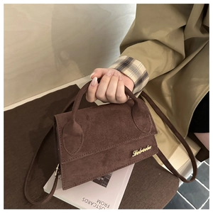 Close-up of a dark brown suede crossbody bag with golden logo and elegant leather handle