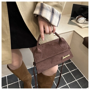 Detail showing the brown suede crossbody bag with gold Leberhu logo and matte finish texture