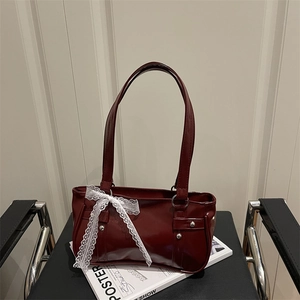 Bolso baguette de charol rojo oscuro con lazo de encaje blanco y remaches de plata