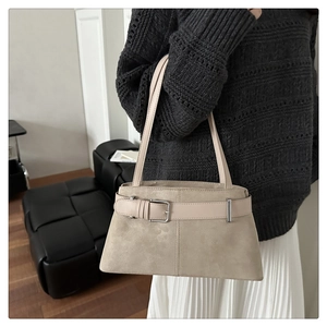 Detail of beige suede and leather tote bag featuring a decorative belt buckle design