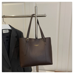 Detail of dark brown leather tote bag with gold lettering and adjustable shoulder strap