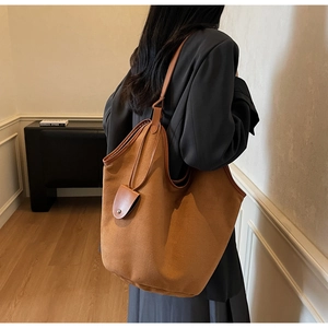 Detail of camel suede tote bag with leather shoulder strap and decorative metal rivets