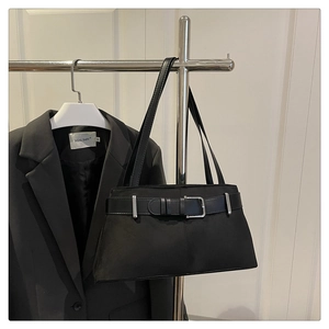 Detail of a black shoulder bag featuring a silver metal buckle and decorative leather belt