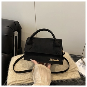 Close-up of black suede crossbody bag with gold logo and elegant top handle detail