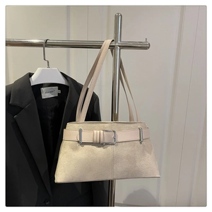 Detail of beige suede tote bag with a decorative metal belt buckle on a black blazer