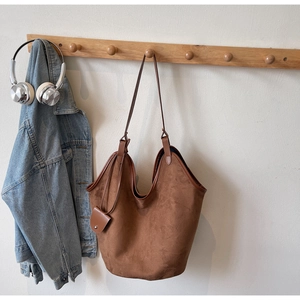Detail of vintage brown suede tote bag with matching mini coin purse on wooden hook