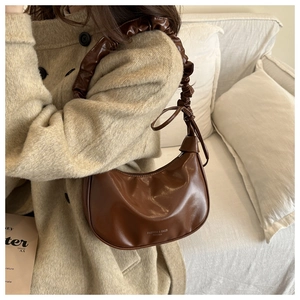 Détail du sac dumpling en cuir marron vintage avec une bandoulière nuage plissée unique