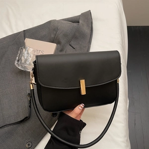 Minimalist black leather shoulder bag with golden buckle in a stylish commute setting