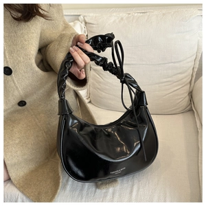 Détail du sac croissant en cuir verni noir avec ruban noué et bandoulière froncée