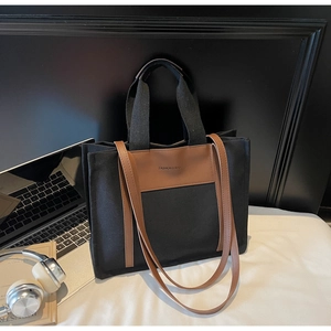 Detail of minimalist black canvas tote with PU leather trim and long shoulder straps