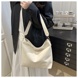 Détail d'un sac hobo en cuir grainé blanc crème avec large bandoulière sur un modèle
