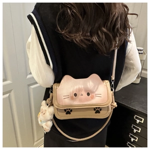 Detail of cute cat face crossbody bag with plush bear charm and paw print patterns