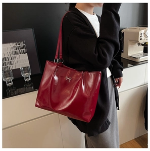 Detail of red leather tote bag with metal bow accent and large capacity design
