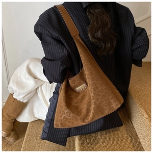 Close-up of brown leopard print tote bag with leather logo tag on a seated model