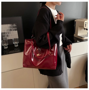 Close-up of deep red glossy leather tote bag featuring a silver metal bow detail