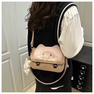 Detail of the cat-shaped crossbody bag featuring paw prints and a plush doll pendant