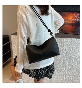 Detail of the black leather bucket bag showing lychee texture and knotted strap detail