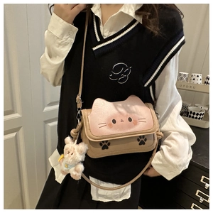 Detailed close-up of a cute cartoon cat crossbody bag with pink ears and plush charm