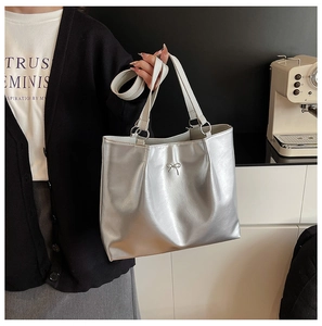 Detail shot of silver metallic tote bag featuring a decorative bow and adjustable strap