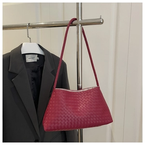 Dettaglio della trama in pelle intrecciata rosso scuro su borsa hobo minimalista