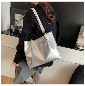 Detailed view of silver metallic tote bag featuring a bow accent and long shoulder straps