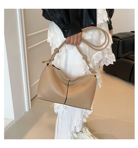 Detailed close-up of a khaki half-moon bag featuring unique knotted strap and gold hardware