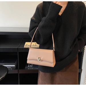 Detail of beige leather underarm bag with metal square buckle and minimalist flap design