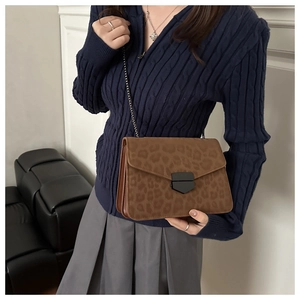 Détail d'un sac bandoulière léopard avec fermoir en métal foncé et fine bandoulière chaîne