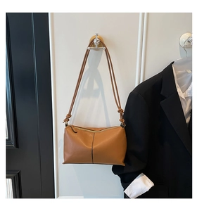 Detail of caramel leather shoulder bag showing smooth zipper and decorative knotted strap