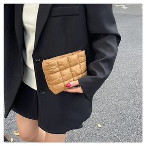 Close-up of brown quilted puffer fabric clutch bag showing grid stitch and soft texture