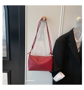 Detail of red lychee grain leather bag with knotted shoulder strap and gold hardware