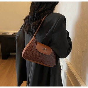 Close-up of vintage brown crocodile embossed shoulder bag with silver metal bow detail