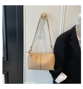 Macro detail of beige pebble texture leather bag with side knot design and golden metal accents