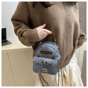 Detail of blue denim mini backpack with cat ears and metallic chain shoulder strap