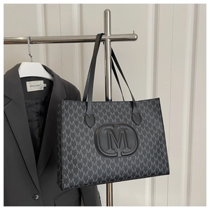 Close-up of monogram pattern and embossed M logo on a dark grey fashion tote bag
