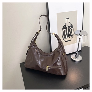 Detail der dunkelbraunen Hobo-Tasche mit glänzendem Finish und goldenem Reißverschluss