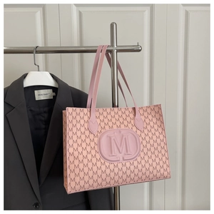 Close-up of pink tote bag with M-letter monogram print and embossed oval logo detail