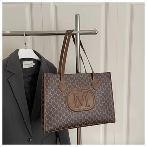 Detail of monogram M print tote bag with brown faux leather strap and central embossed logo